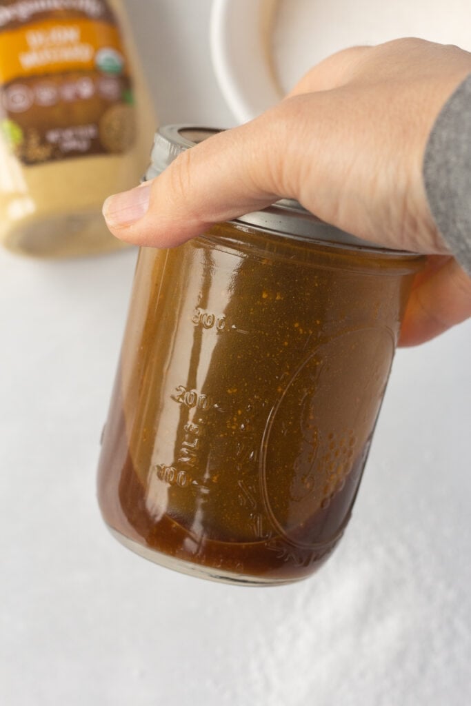 A brown chicken marinade being shaken in a closed mason jar.