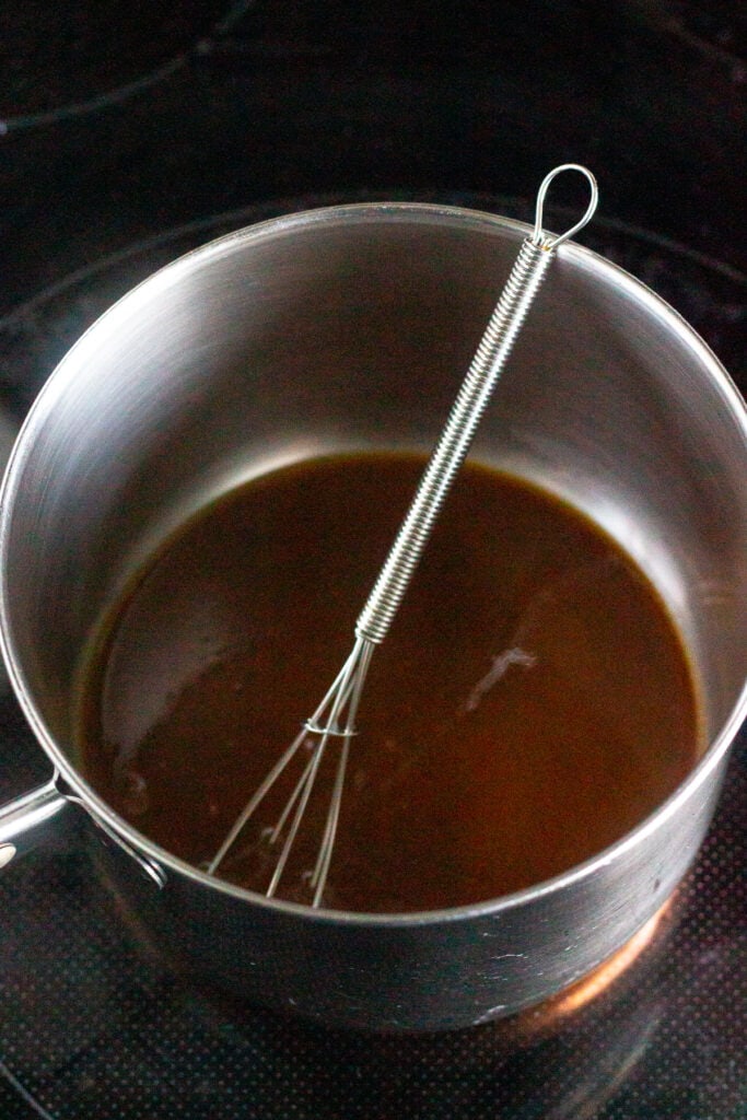 Chicken marinade in a small sauce pan with a whisk in it.