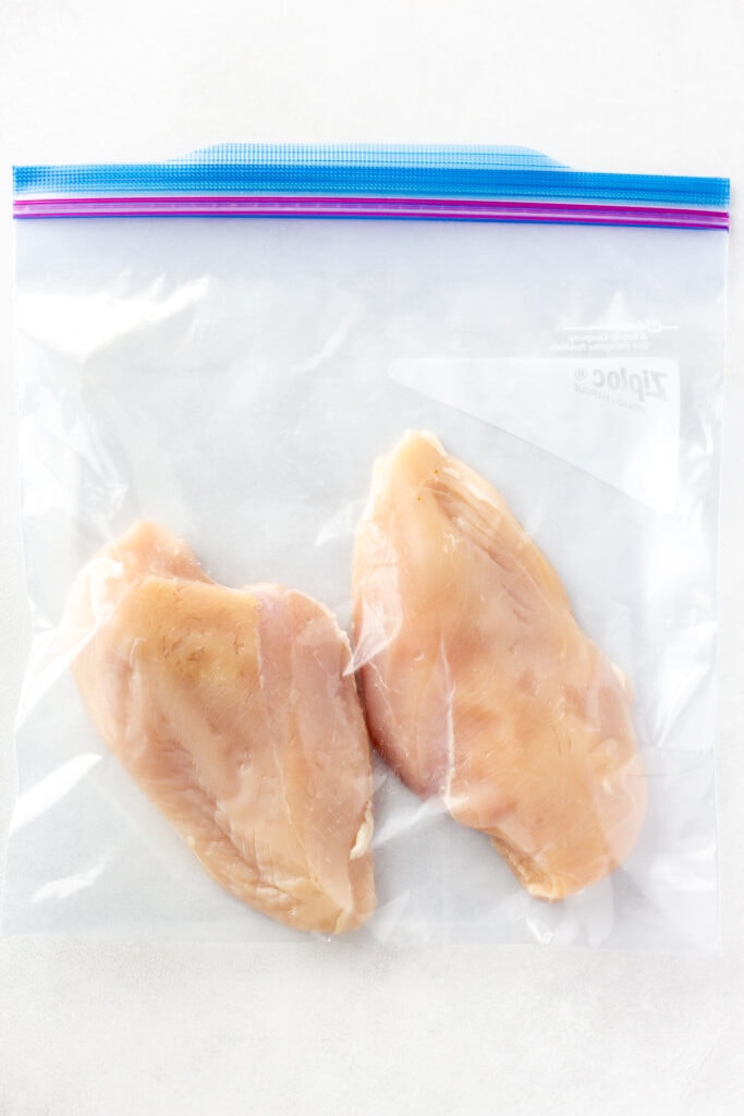Two chicken breast in a ziploc bag on a white background.
