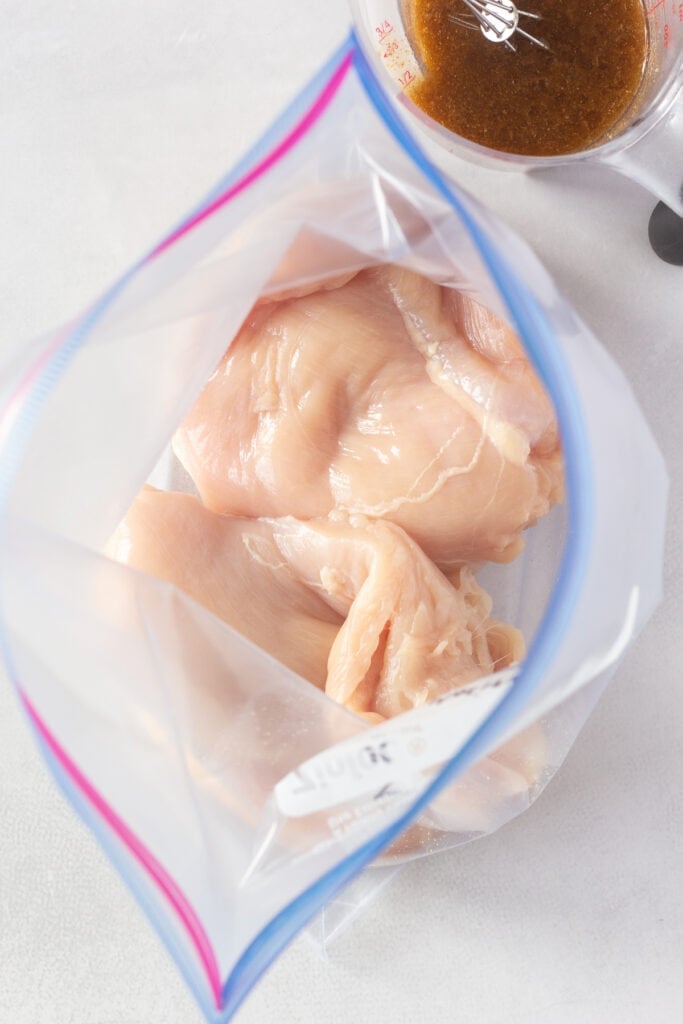 Top down shot of raw chicken breasts in a ziploc bag.