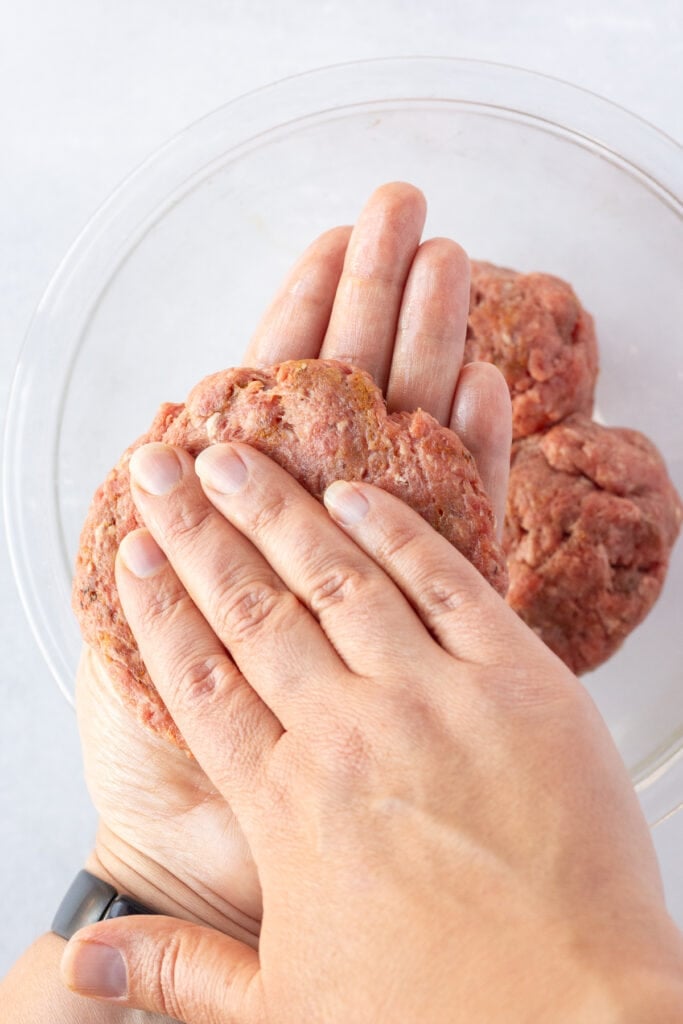 Close up of hands making raw burger meat into a hamburger patty.