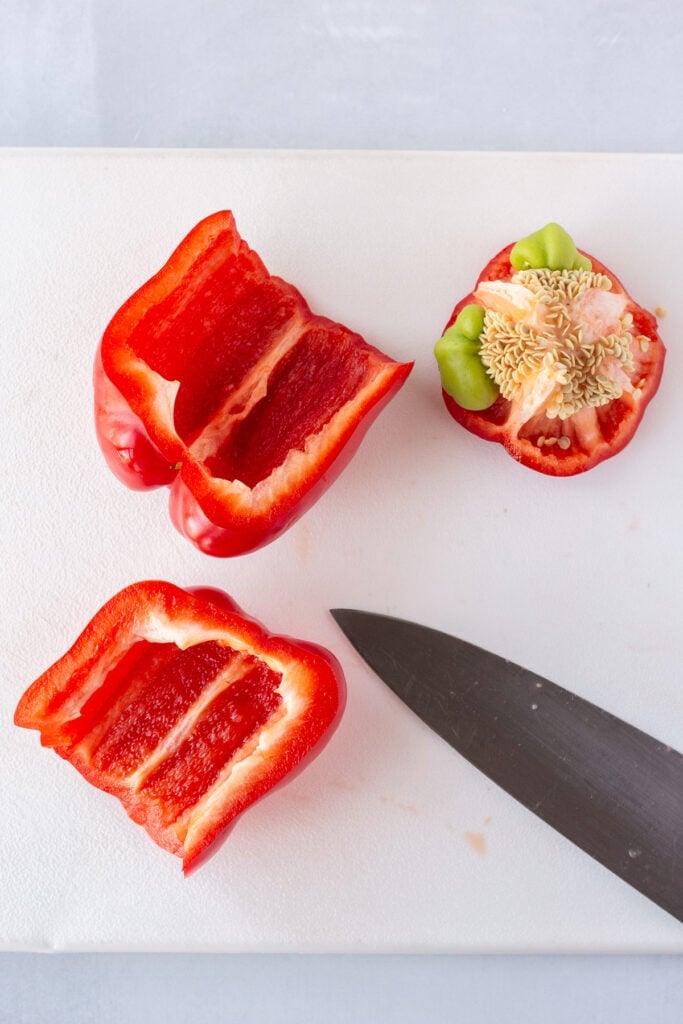 Cutting and cleaning a red bell pepper on a white cutting board