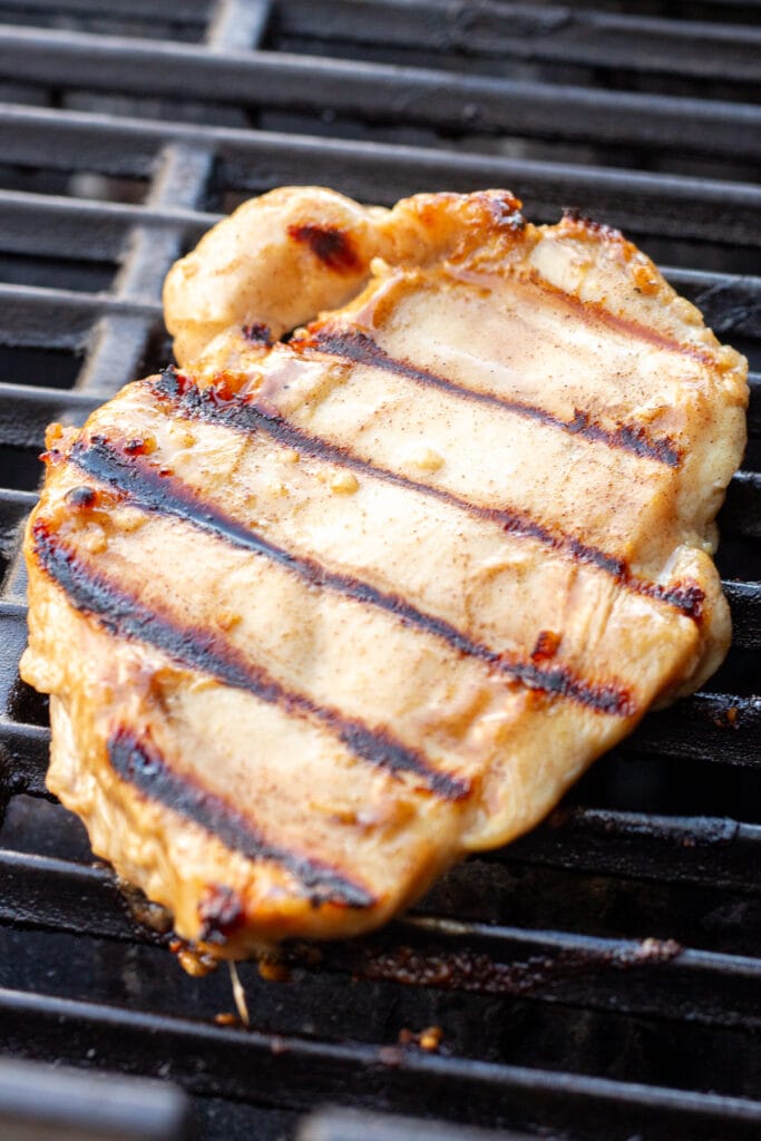 Close up of a honey mustard chicken breast on a hot grill.