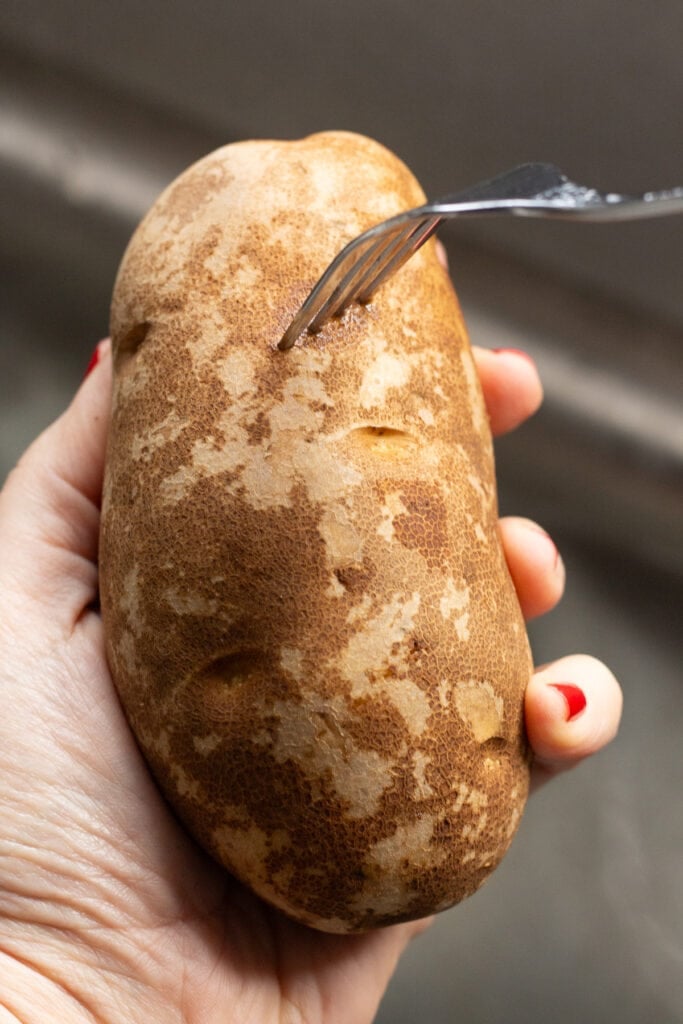 A fork poking into a russet potato.
