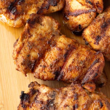 Top down shot of grilled chili lime chicken thighs on a wood cutting board.