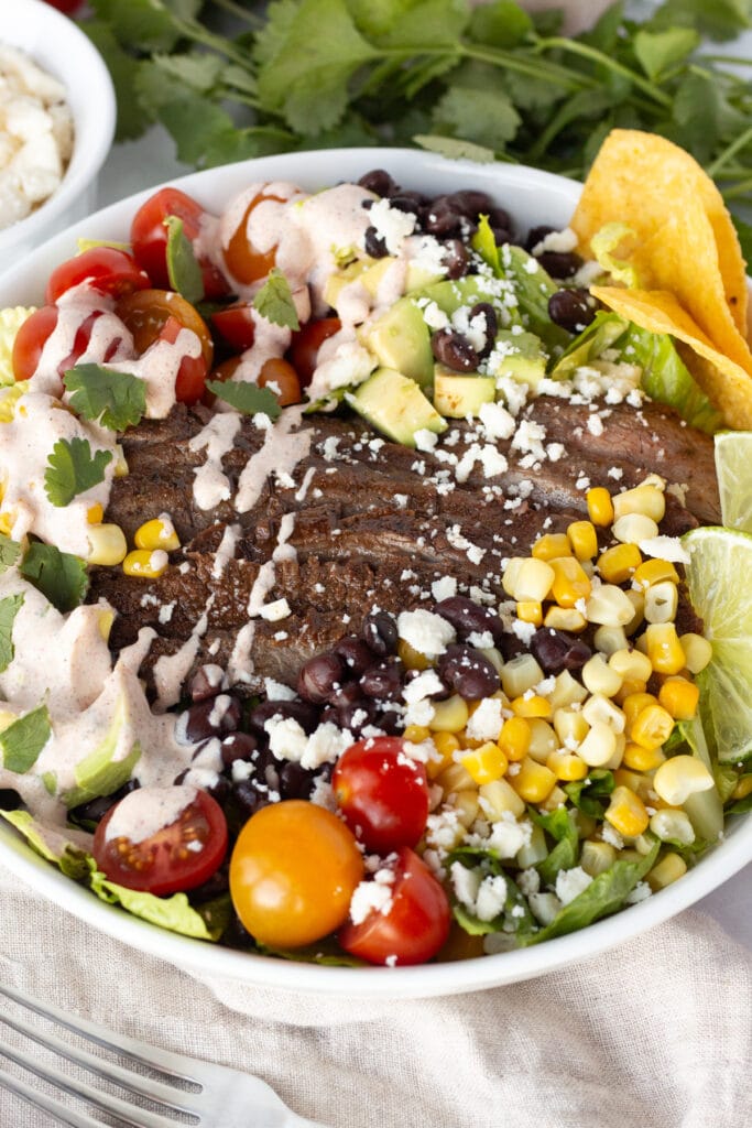 Close up of a low white bowl with steak taco salad in it.