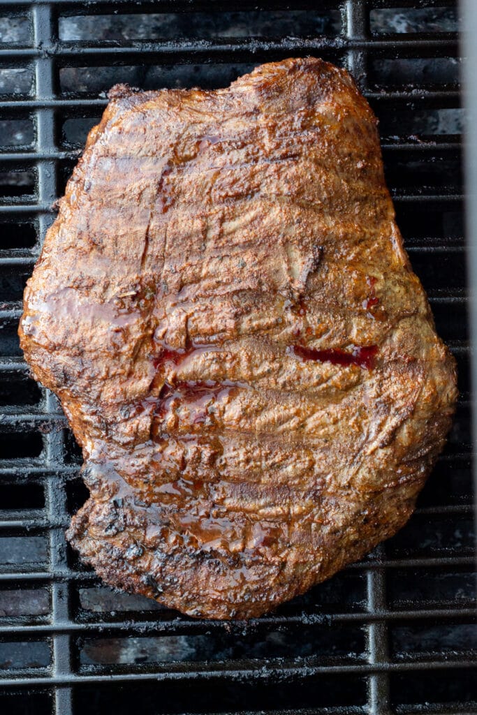 Top down shot of a cooked flank steak on a gas grill.