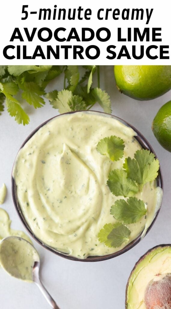 Pinterest image with a picture of green avocado cilantro lime sauce in a bowl with cilantro leaves on top. The ingredients for the sauce surround the bowl, as well as a spoon with sauce on it. At the top is a white box with black text that reads "5-minute creamy avocado lime cilantro sauce".