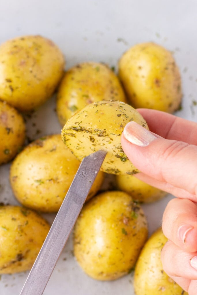 Close up of half a yellow potatoes being put onto a metal skewer.